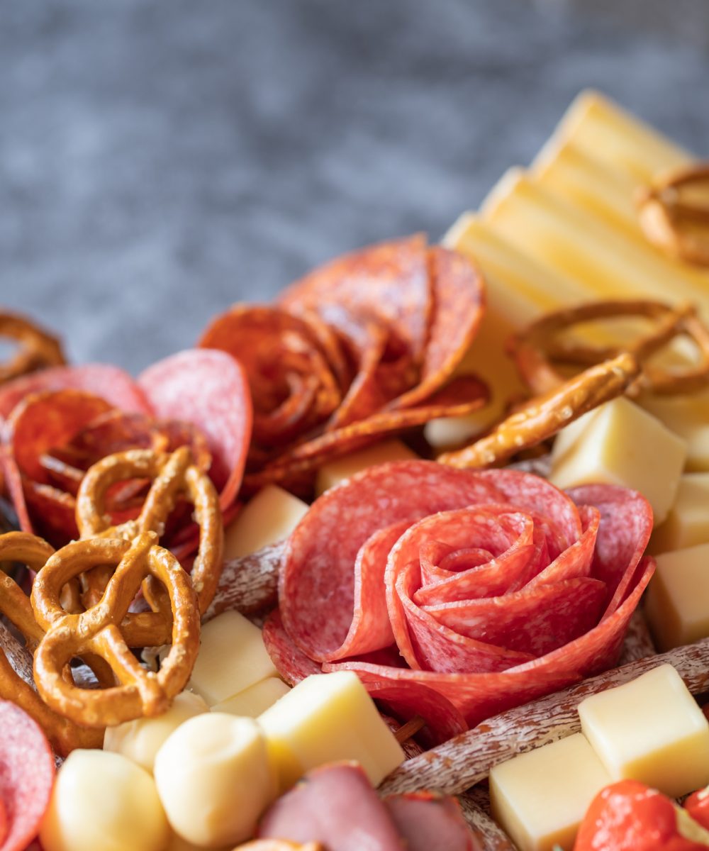 Cutting board with ham, salami, cheese, cracker and olives on a wooden board. Copy space